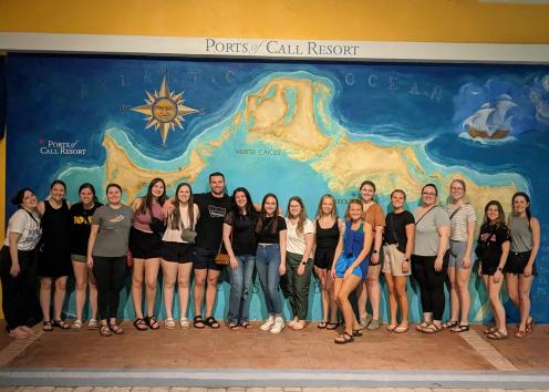 Group of students in front of a colorful wall with a mural of a map