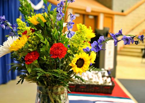 Flowers in a vase on the table of awards, tassels and scrolls. 